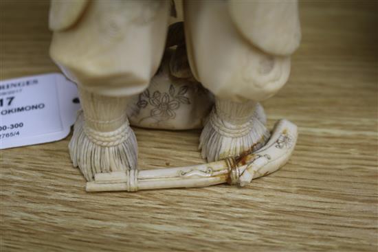 A Japanese carved ivory okimono of a huntsman, Meiji period, holding a hawk and a brace of birds